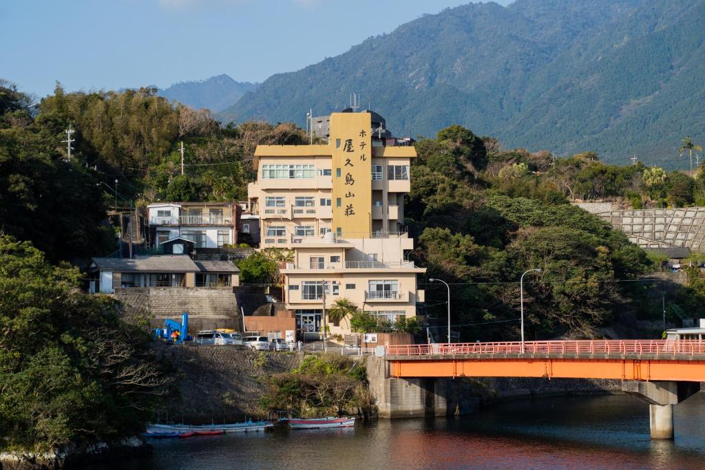 屋久岛屋久岛山莊酒店的河岸边的一座建筑物,有一座桥梁
