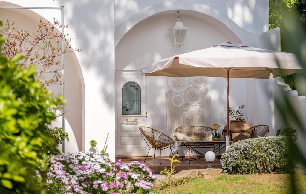 阿纳卡普里伊尔索格诺住宿加早餐酒店的一个带遮阳伞、椅子和鲜花的庭院