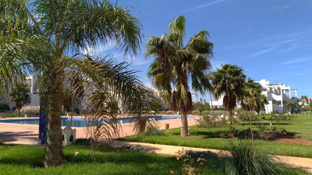 萨伊迪耶Chez Younès Appartement Marina Saidia Ap8的一个带游泳池和棕榈树的度假村