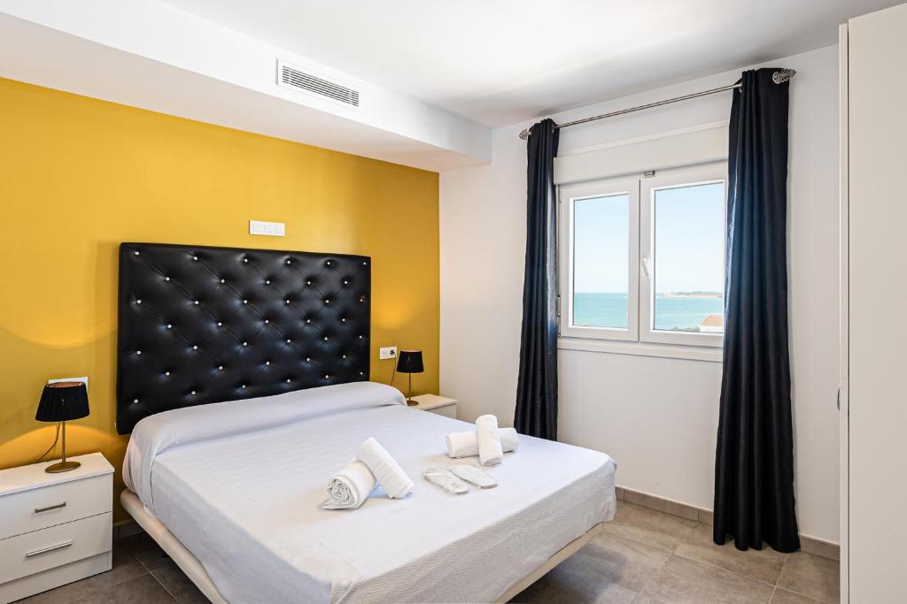 科尼尔-德拉弗龙特拉Apartamentos Turísticos La Boutique del Mar的一间卧室设有一张大床、黄色的墙壁和窗户