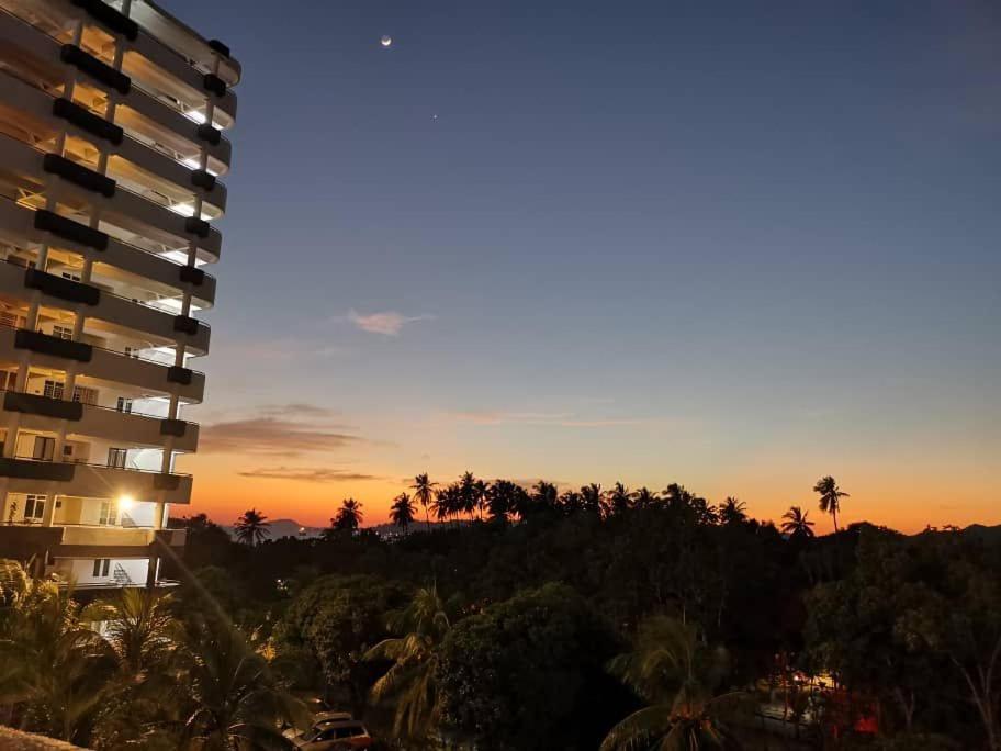 瓜埠Bleu Martin Families Suite Apartment的享有大楼和棕榈树的日落美景