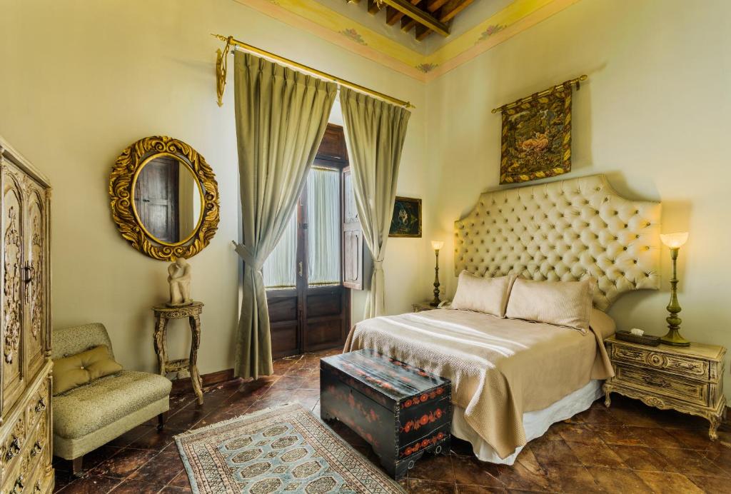 瓜达拉哈拉卡萨佩多洛泽酒店的一间卧室配有一张床、一把椅子和镜子