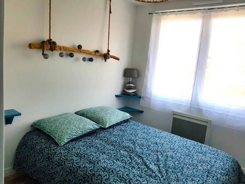 鲁瓦扬Appartement Royan, 200 m de la PLAGE的一间卧室配有一张带蓝色毯子的床和窗户。