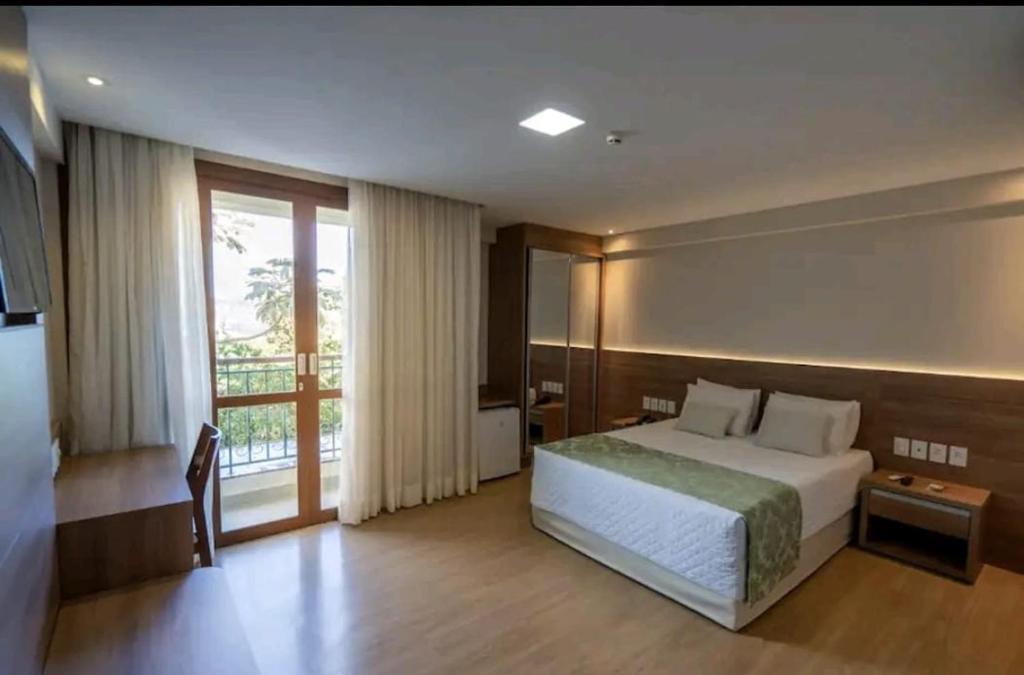 多明戈斯马丁斯SUÍTE EM PEDRA AZUL - Condomínio VISTA AZUL的一间卧室设有一张床和一个大窗户