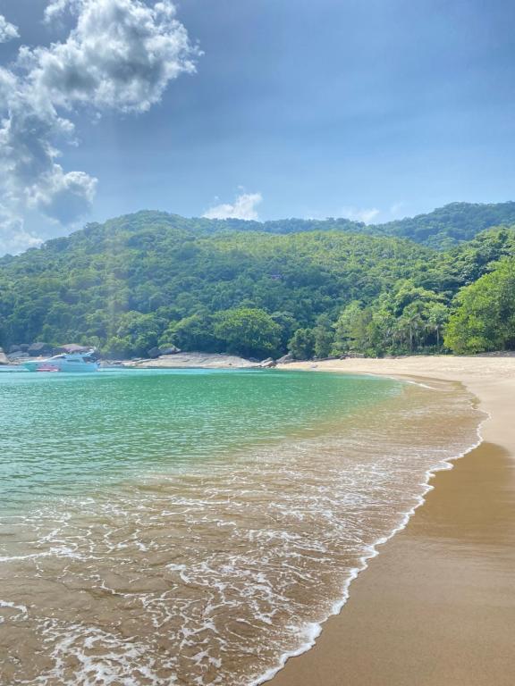伊利亚贝拉Suítes Canto do Nema的一片绿水和树木环绕的海滩