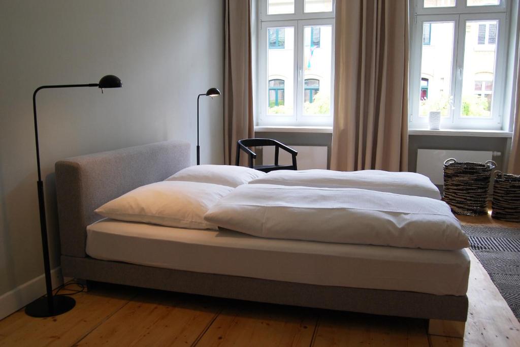 莱比锡SCHÖNER WOHNEN IM DENKMAL - großzügig geschnitten, kostenfreies WLAN的配有窗户的客房内的一张带白色床单和枕头的床