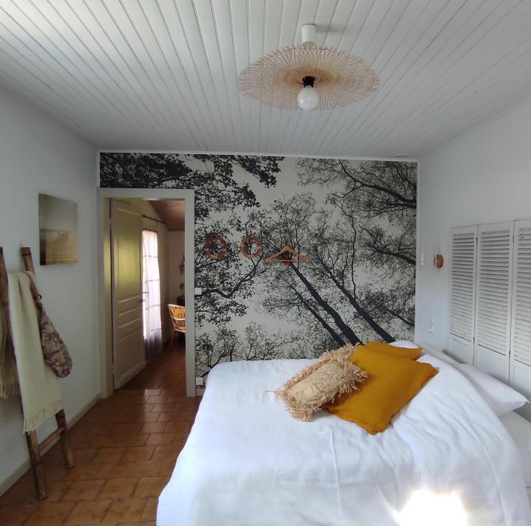 米米藏Les jardins de Mimizan的卧室配有一张白色床,墙上挂有绘画作品