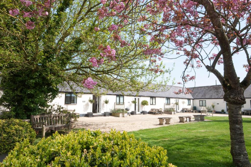 沙夫茨伯里Stable Cottage, Whitebridge Farm的享有白色建筑庭院和粉红色花卉的景色