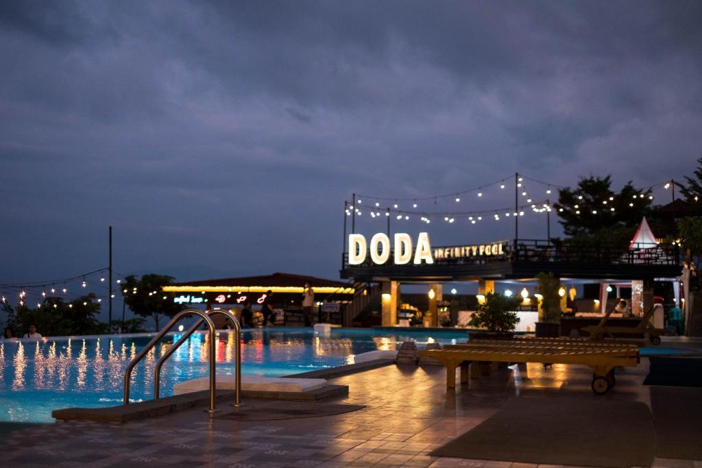 帕卢Bukit Indah Doda Hotel & Resorts的夜间游泳池,有 ⁇ 田标志