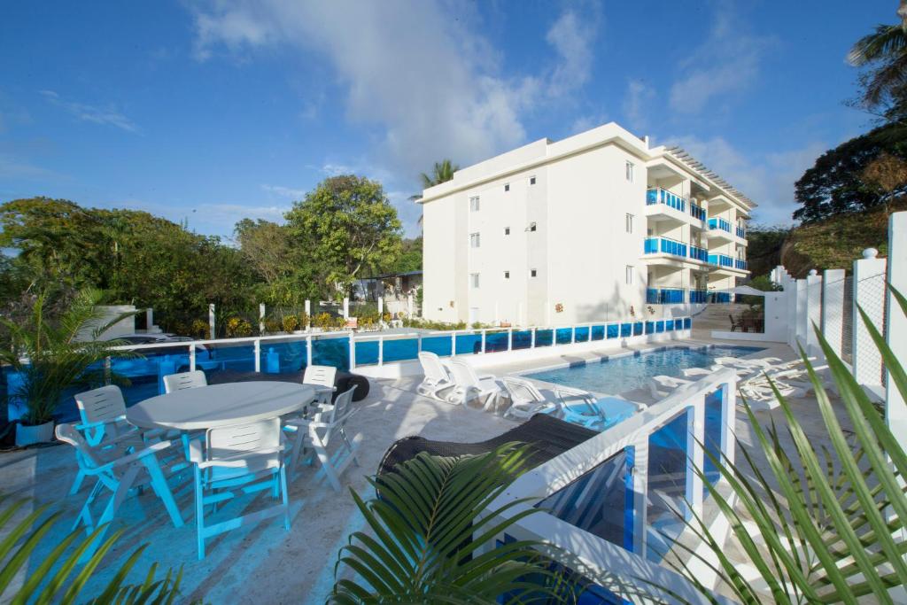 苏莎亚CoralK Apartments Sosúa的大楼旁的游泳池配有桌椅