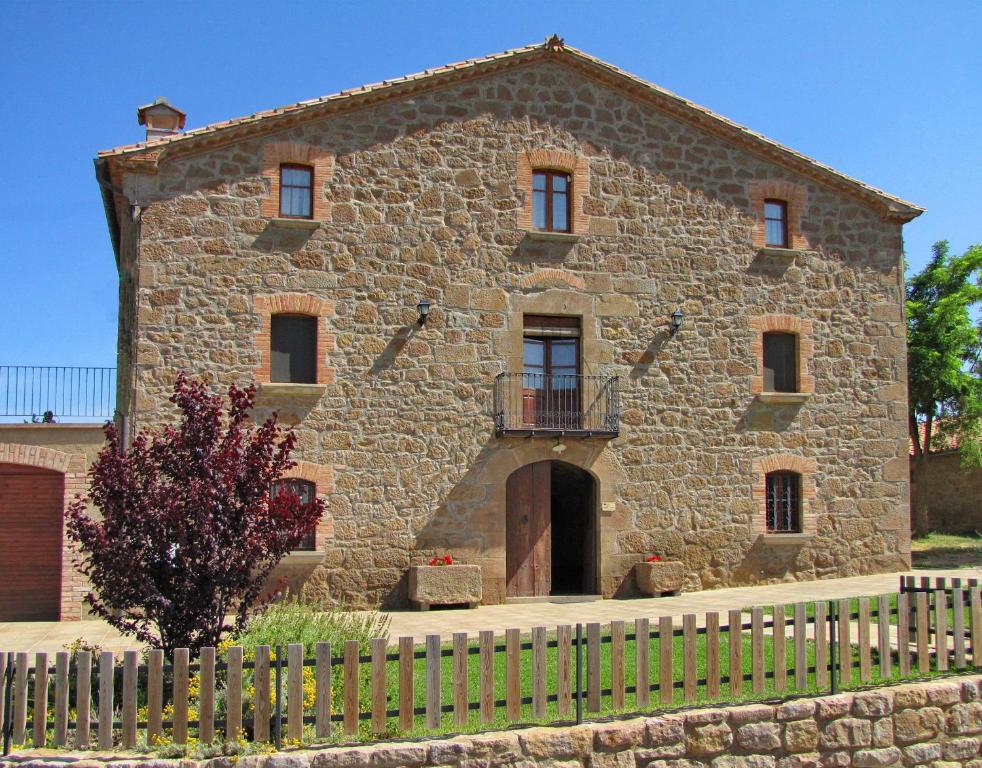 LladursCasa Serra de Dalt的一座古老的石头建筑,前面有栅栏