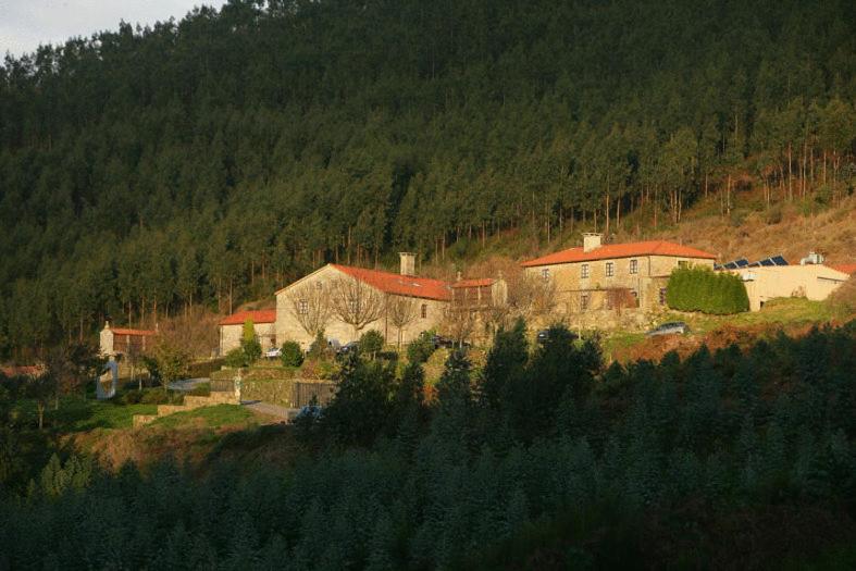 圣地亚哥－德孔波斯特拉卡萨格兰德巴乔酒店的山丘上树木繁茂的一群建筑