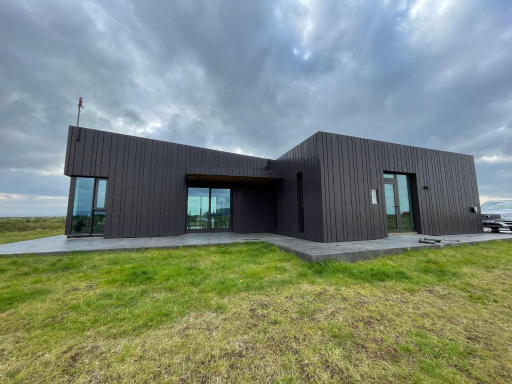 海拉Fögruvellir Country House的草坪上带玻璃门的黑色建筑