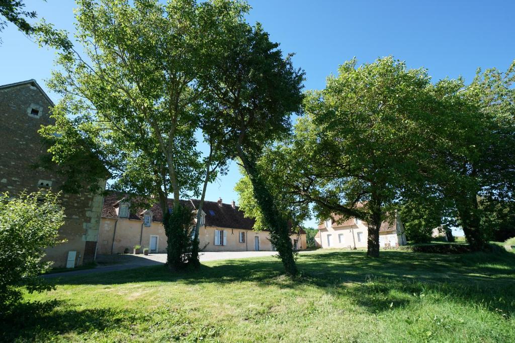 Cour-Maugis-sur-HuisneChambres d'hôtes du Bistrot des écuries的一群树木在一座有建筑物的院子中