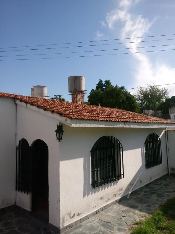 科尔多瓦Hostel Alto Alberdi的白色的房子,设有两扇窗户和屋顶