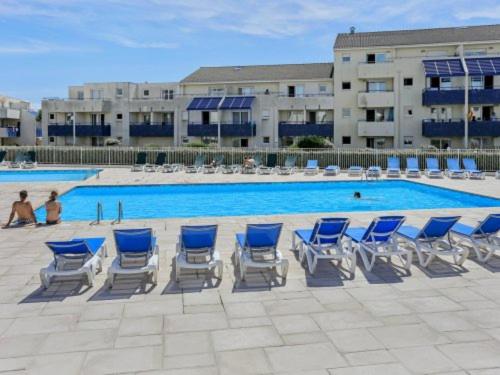 拉卡诺奥肯Appartement Climatisé avec Piscine & Mer Bleu Marine的一组蓝白色椅子和一个游泳池
