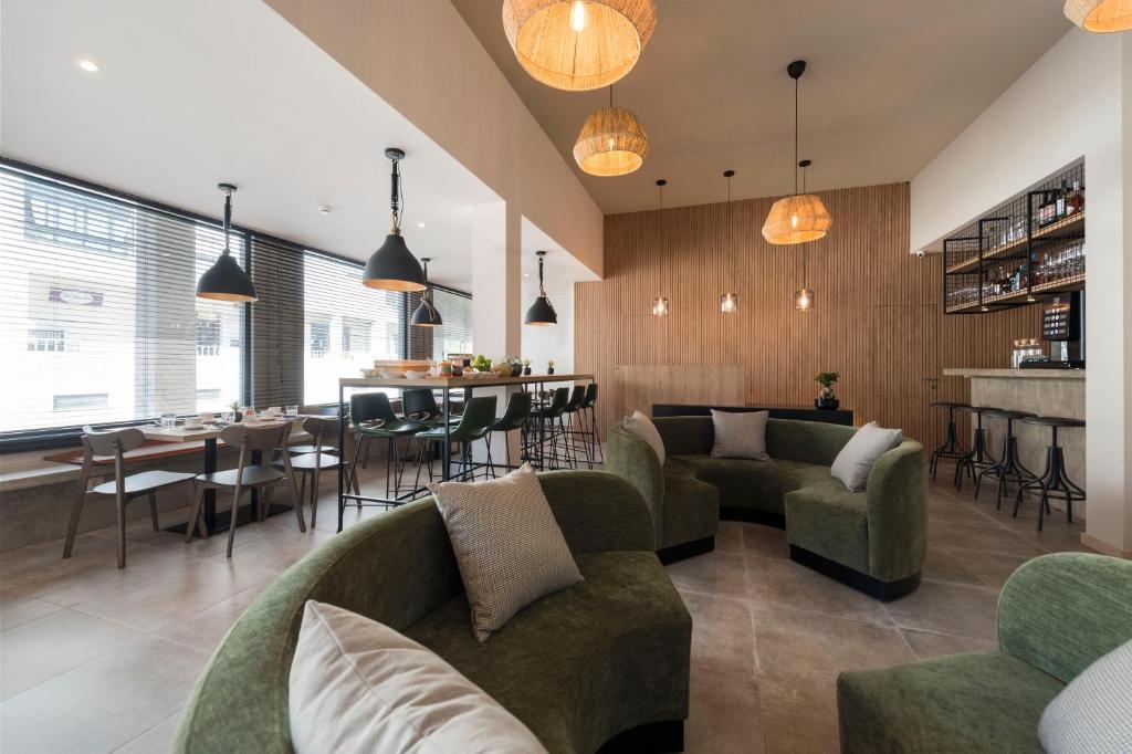 新普罗恩萨Oliva Welcoming Apartments的一间带绿色沙发的客厅和一间酒吧