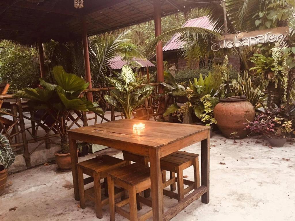 达叻府苏察纳里兰戈普度假村的花园里种有植物,设有木桌和长凳
