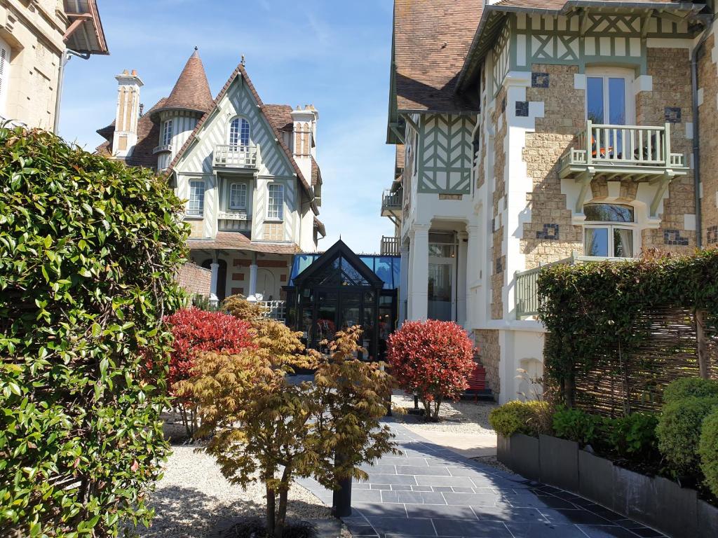 多维尔Villa Augeval Hôtel de charme & Spa的庭院里一排种有树木的房屋