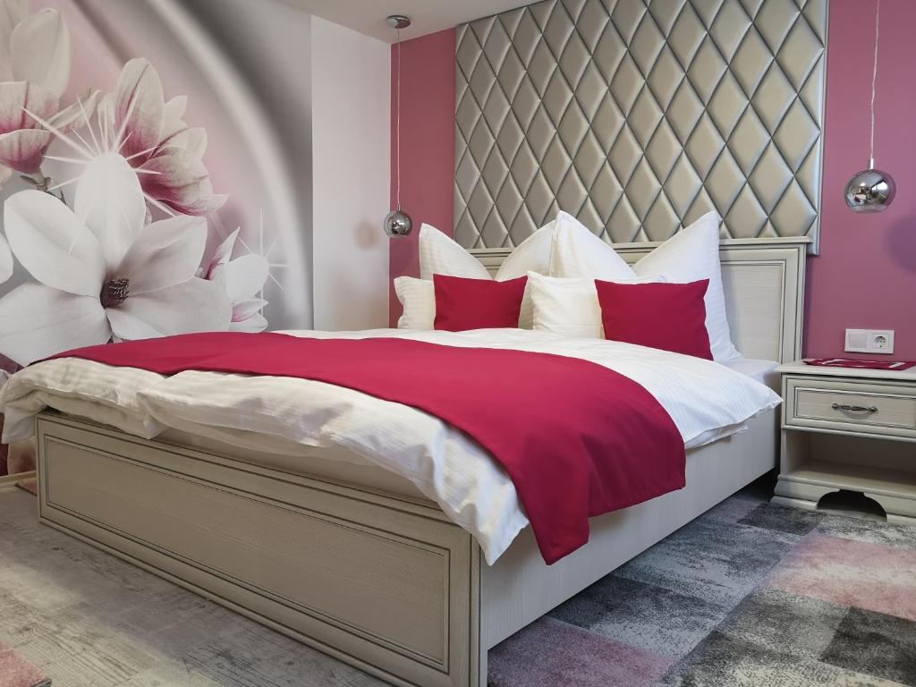 Herend安娜旅馆的一间卧室配有一张带红色和白色枕头的大床