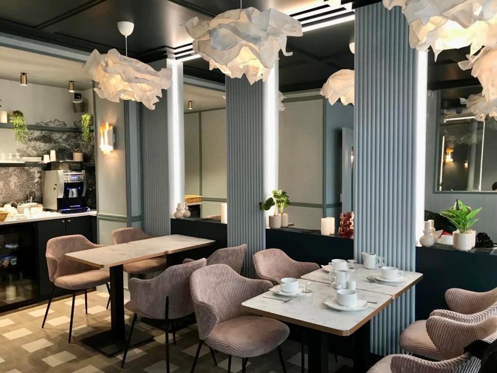 巴黎阿玛德酒店的用餐室配有桌椅和吊灯。