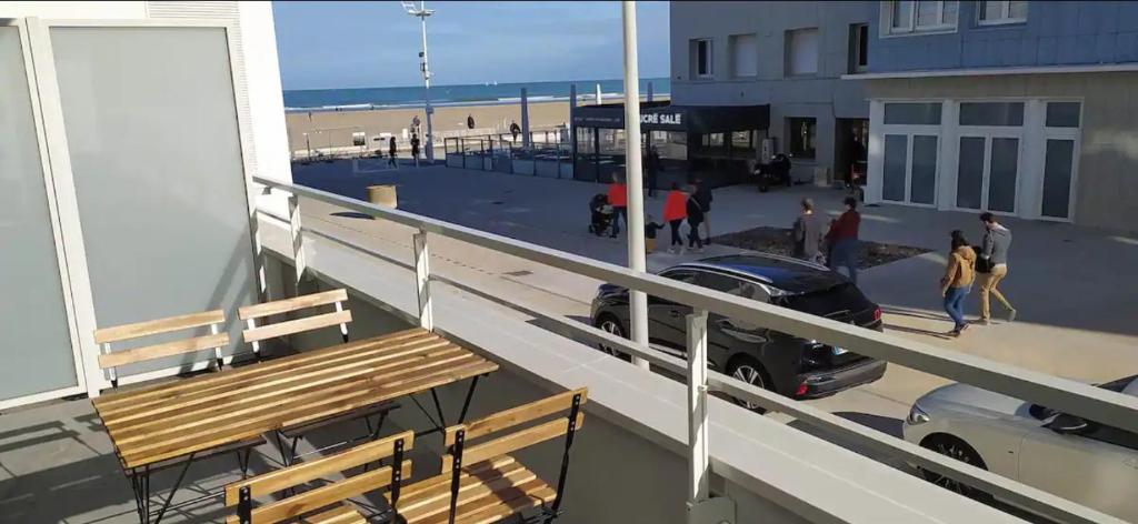 敦刻尔克Bel appt neuf - vue mer - terrasse - parking privé的海滩上的阳台配有长凳和汽车