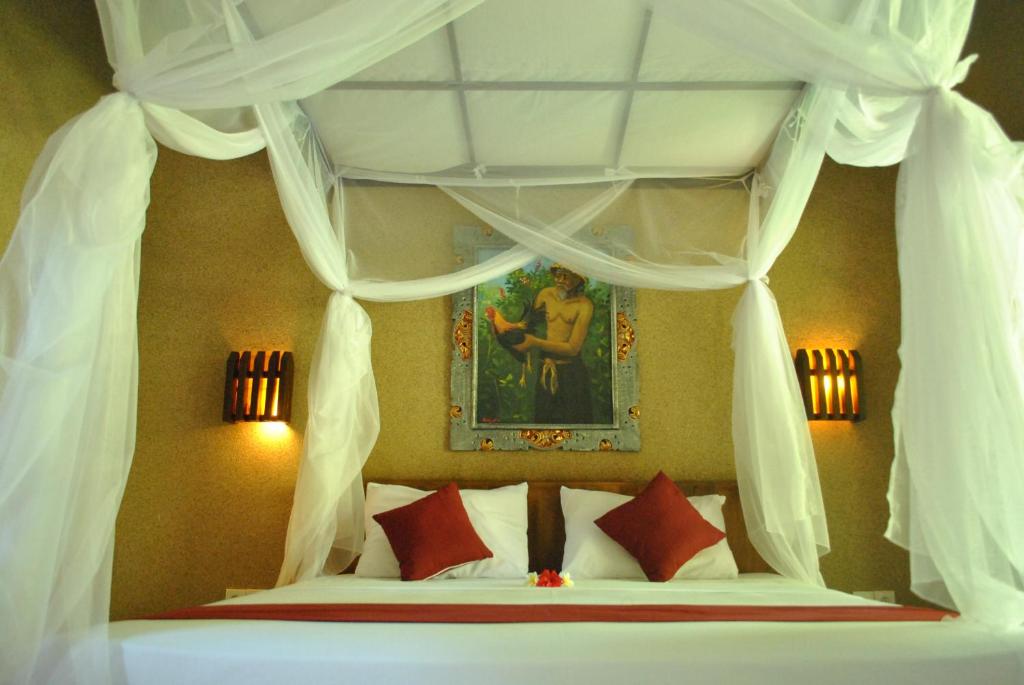 佩母德兰彭多克拉哈余旅馆的一间卧室配有一张带红色枕头的天蓬床