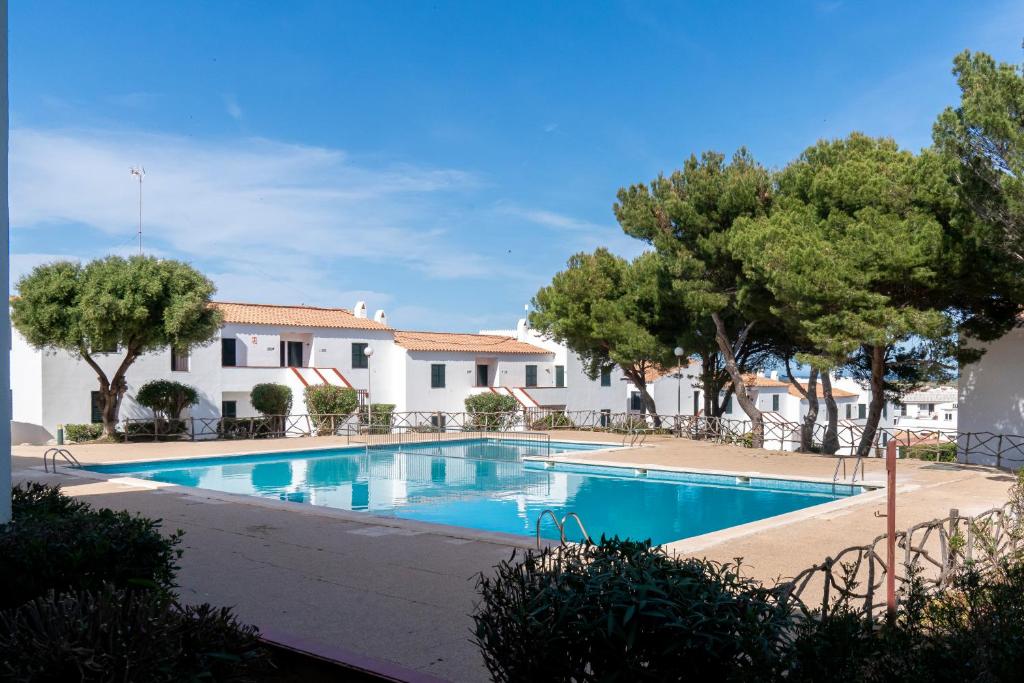 阿雷纳尔登卡斯特尔Apartamento Menorca Arenal d'en Castell的一座建筑前的树木游泳池