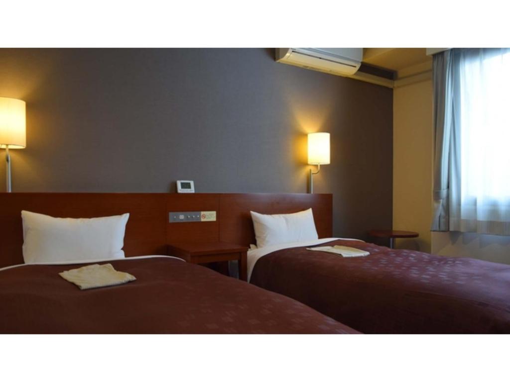 鸟取市Hotel RESH Tottori Ekimae - Vacation STAY 47411v的酒店客房设有两张床和两盏灯。