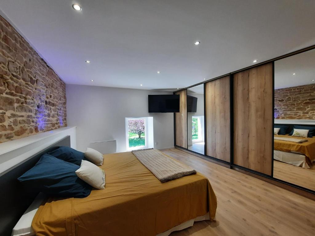 LonnyLes étangs du moulin d'Harcy的一间卧室设有一张大床和砖墙