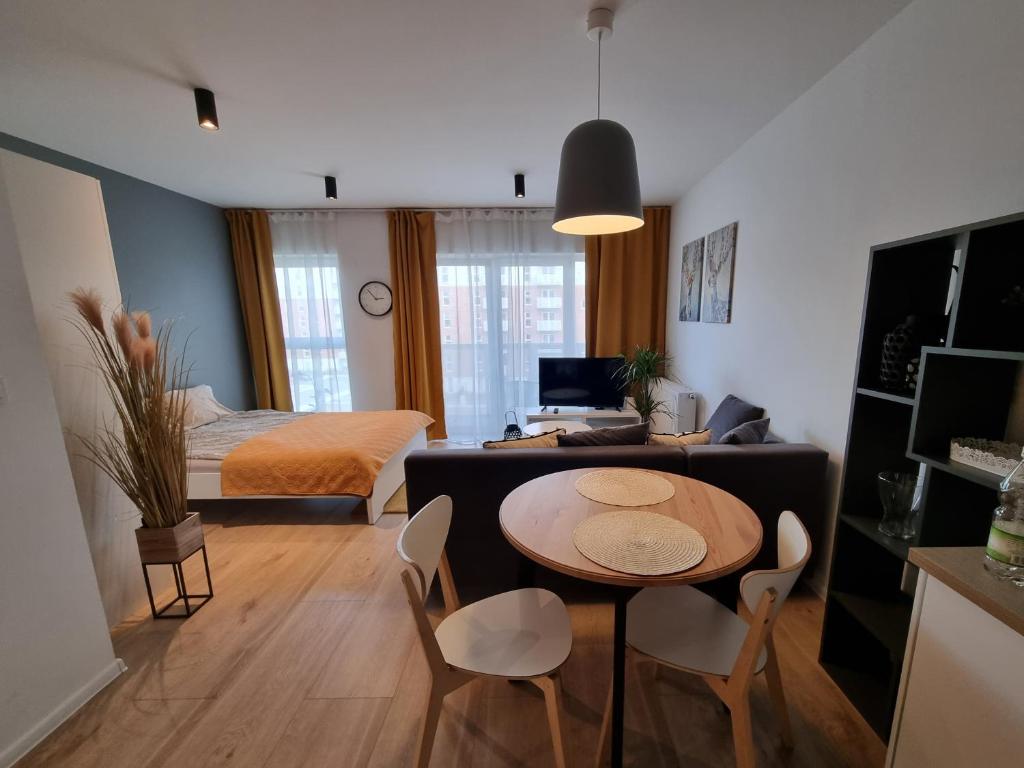 罗兹Apple Apartments - Wróblewskiego PRYWATNE MIEJSCE PARKINGOWE的一间带桌子的客厅和一间卧室