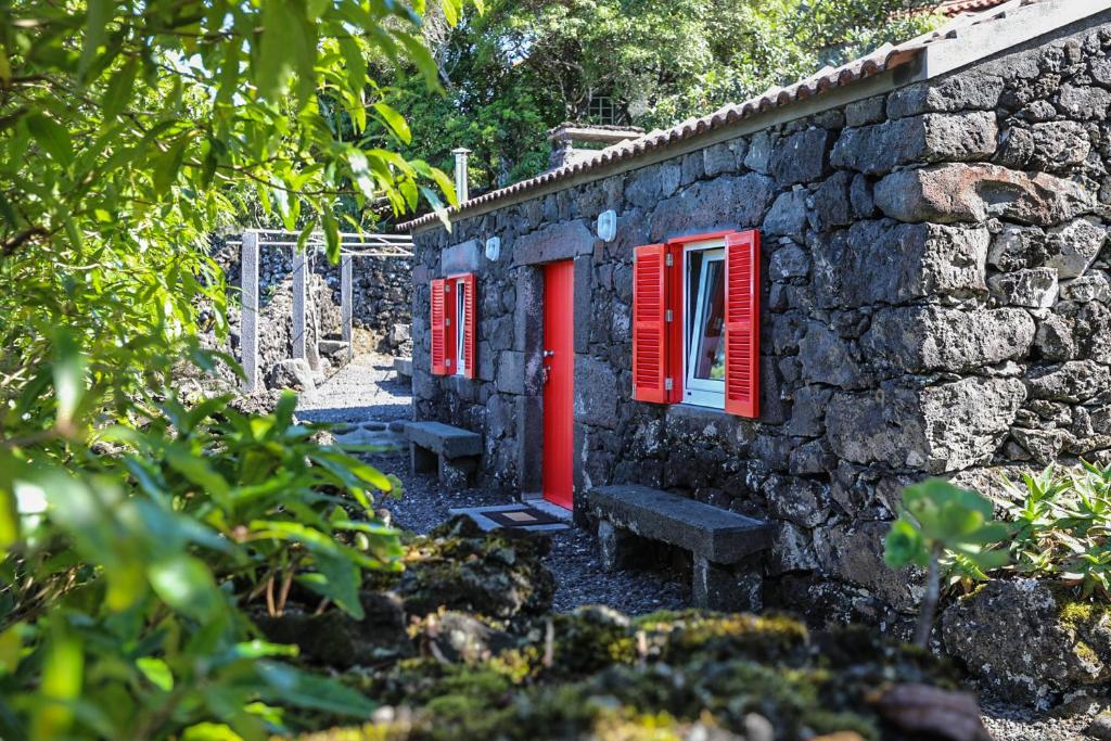 圣罗克杜皮库Adega Baía Azul - The essence of Pico的一座石头建筑,设有红色的窗户和长凳