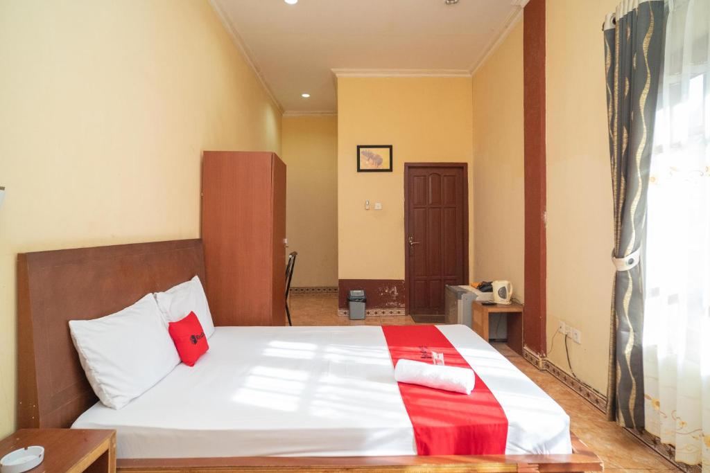 AsemasemRedDoorz at Jl Ahmad Yani Asam Asam的一间卧室配有红色和白色枕头的床