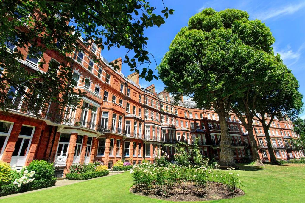伦敦The Franklin London - Starhotels Collezione的一座大红砖建筑,院子中有一棵树