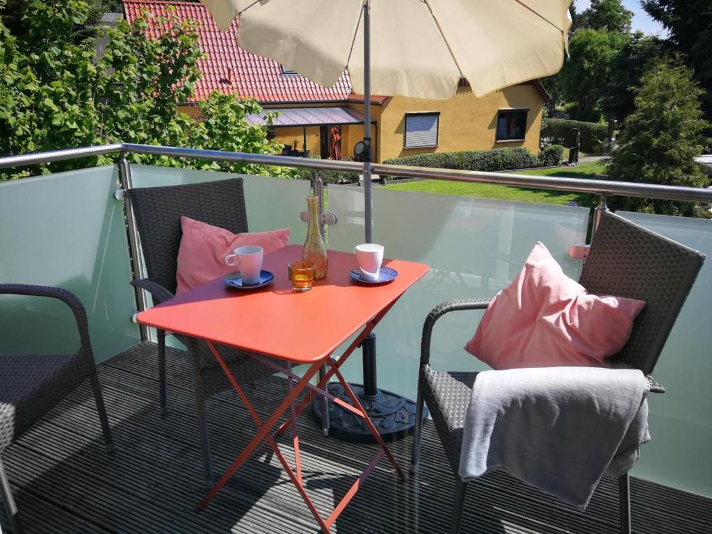 博恩Ferienwohnung Marie in Born的阳台的红色桌子,配有椅子和雨伞