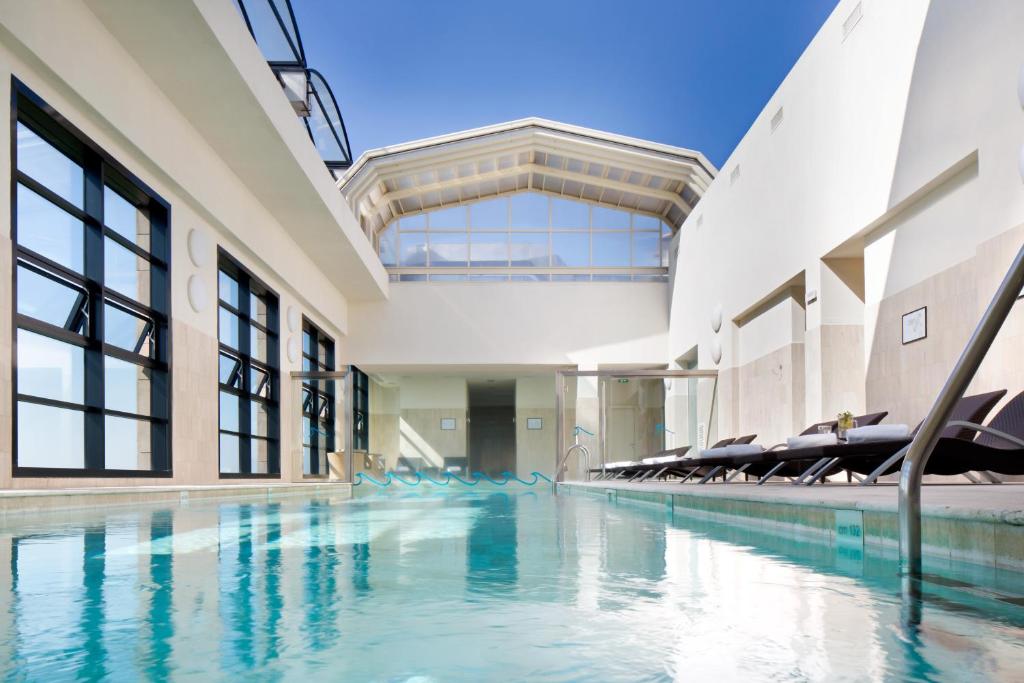 萨龙诺米兰星际大酒店的一座带椅子的室内游泳池,位于一座建筑中