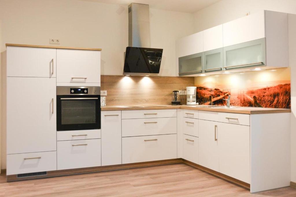 达默Zur Strandwiese W3的白色的厨房配有白色橱柜和电器