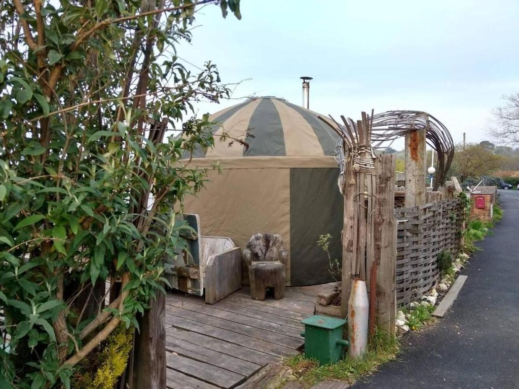 本布里奇Cosy and Inviting Waterside Luxury Yurt的坐在街道旁木甲板上的帐篷