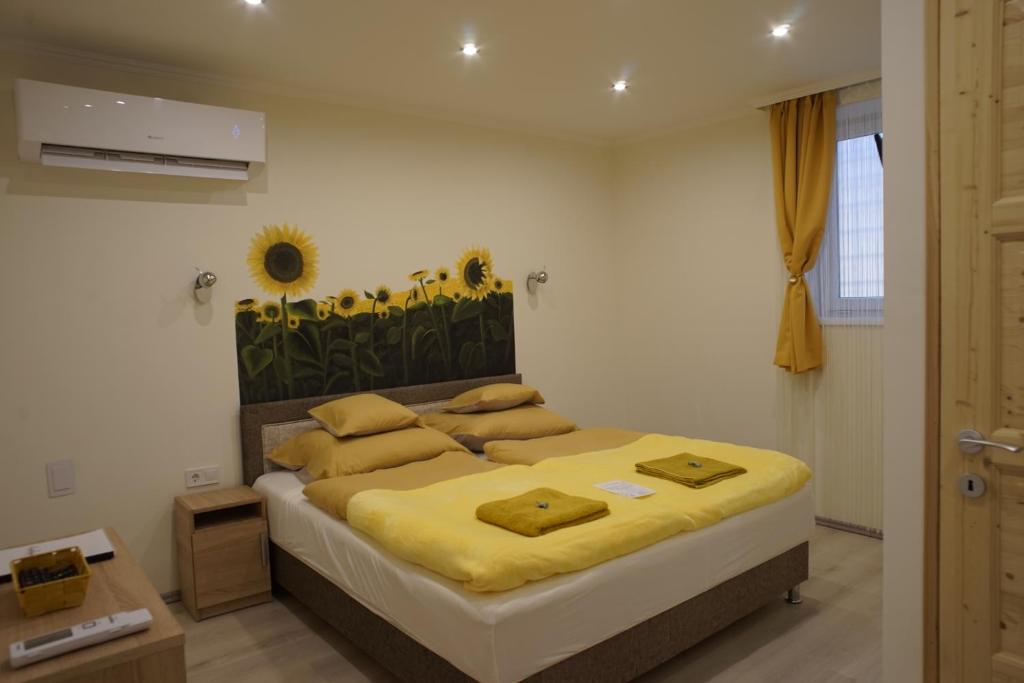 小克勒什Csengő Vendégház的卧室配有一张带黄色床单和鲜花的墙壁床。