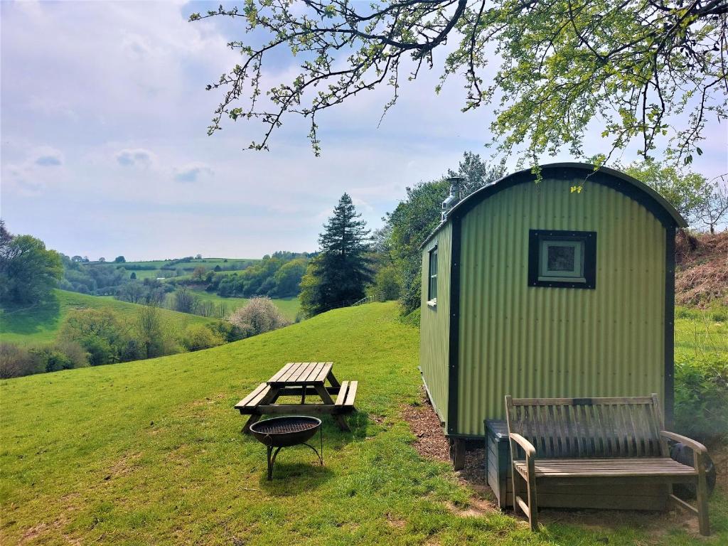 昆布兰Usk Valley Shepherd's Hut的绿色棚子,带野餐桌和长凳