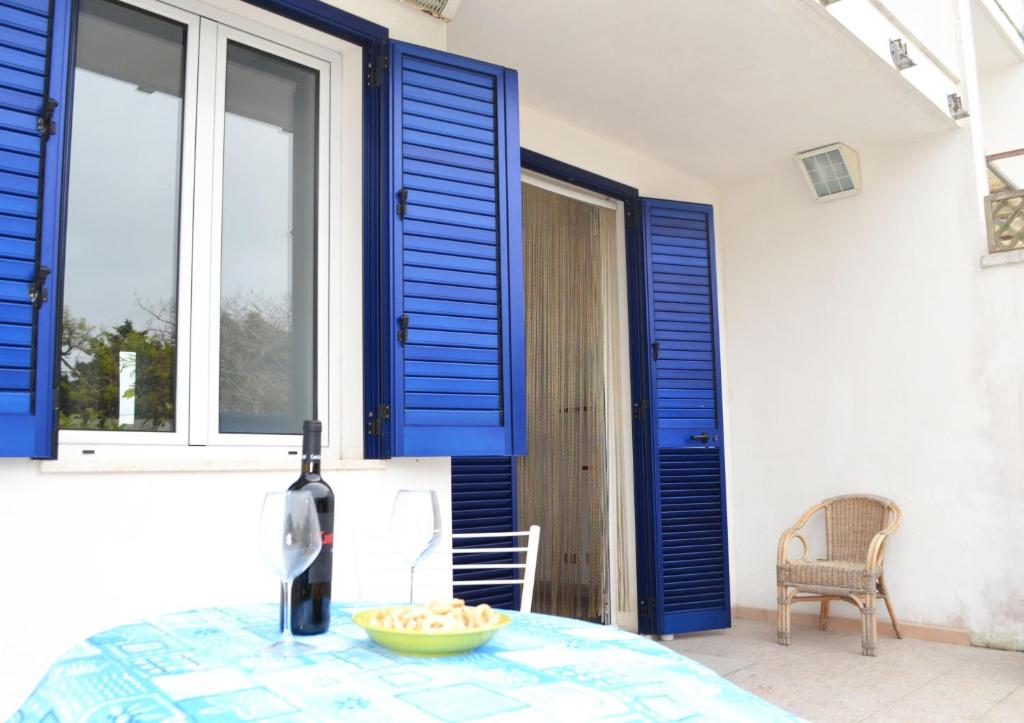 新福卡Villetta vicino spiaggia 4 posti的一间设有蓝色百叶窗和桌子的用餐室