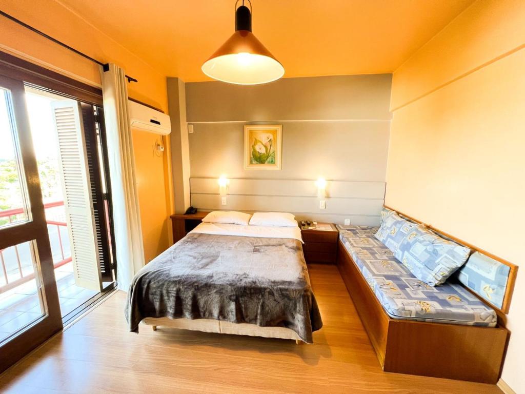 SapirangaHotel das Rosas的一间卧室配有一张床和一张沙发