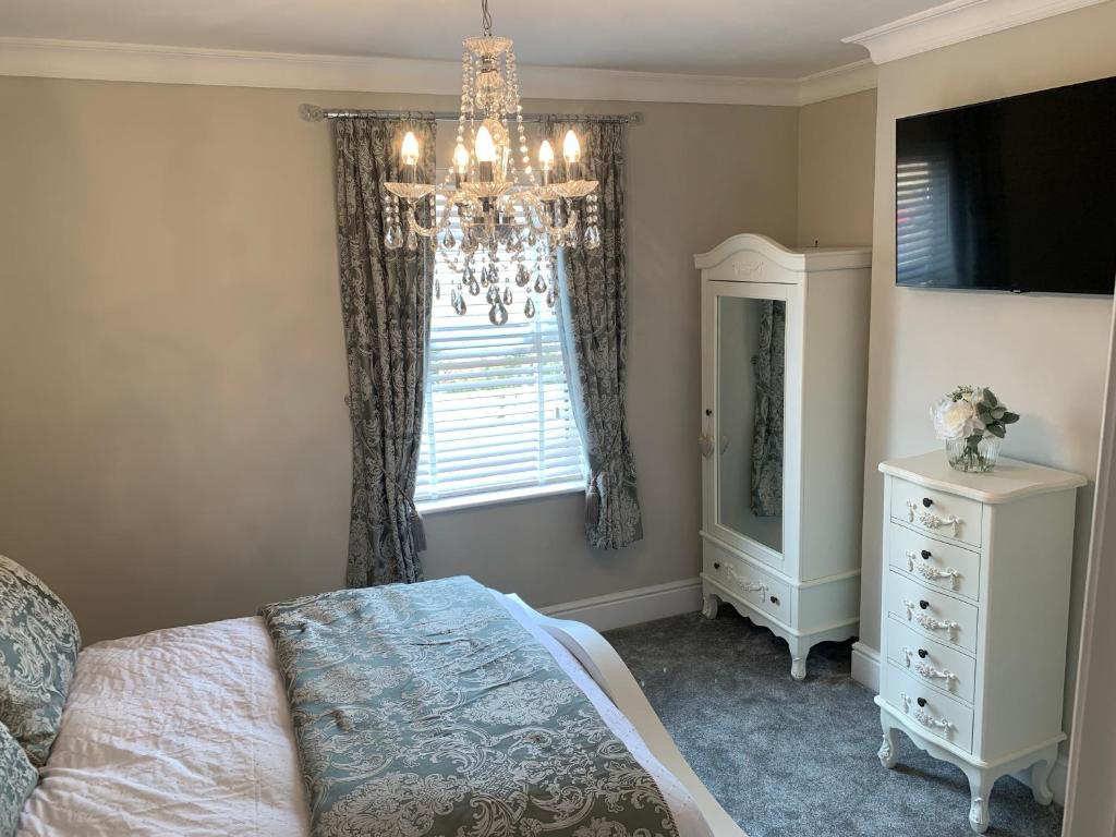 斯坦福德Luxury House, central Stamford with parking的一间卧室配有吊灯、一张床和一个窗户。