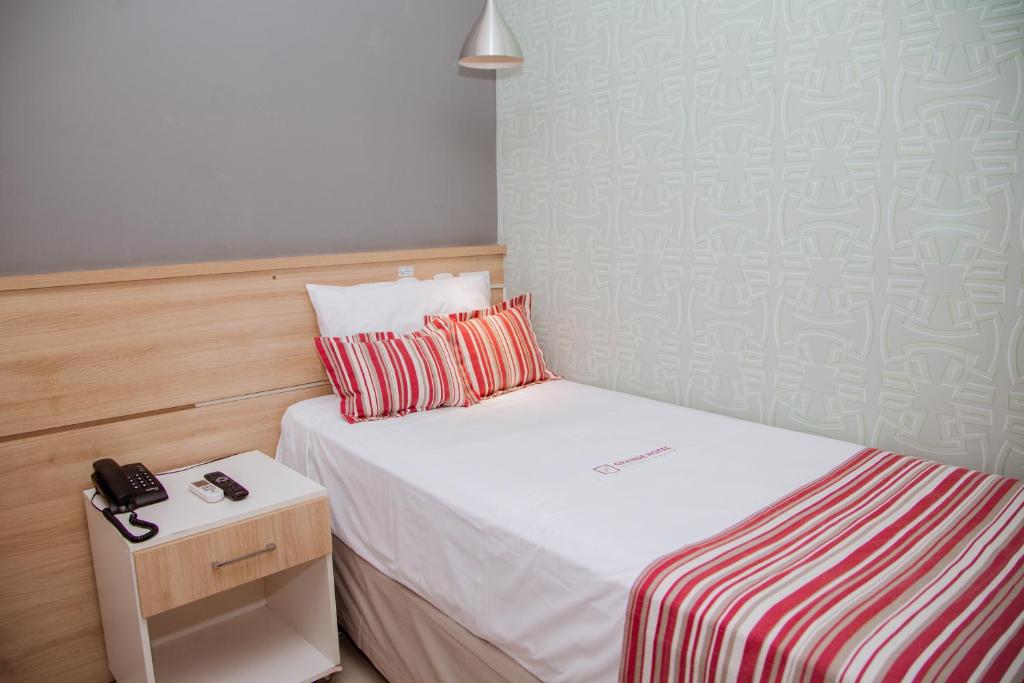 伊帕廷加Grande Hotel Ipatinga的小卧室配有一张床和床头柜上的电话