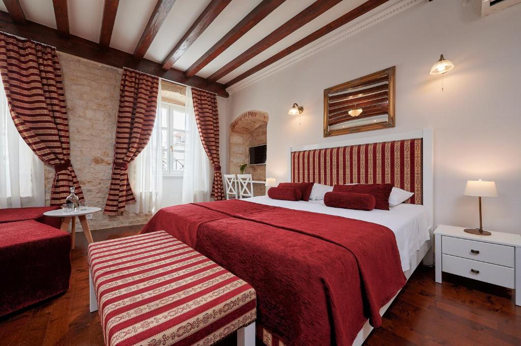 特罗吉尔中央广场宫殿旅馆的一间卧室设有两张带红色床单的床和窗户。