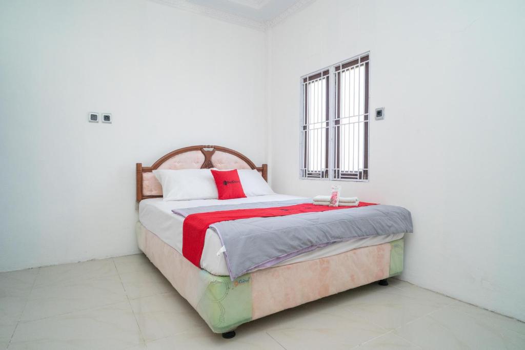 班贾尔马辛RedDoorz Syariah near Jalan A Yani KM 8 Citraland的白色卧室配有红色枕头的床