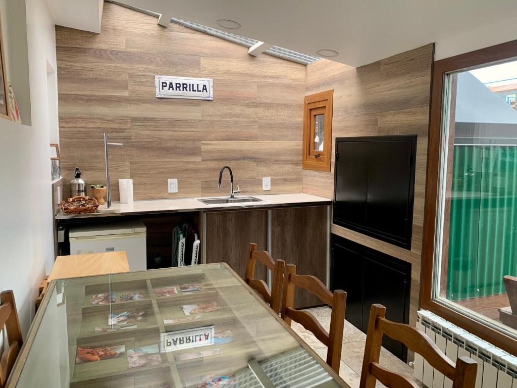 乌斯怀亚Increible Casa ideal Familias的厨房配有玻璃桌、椅子和水槽