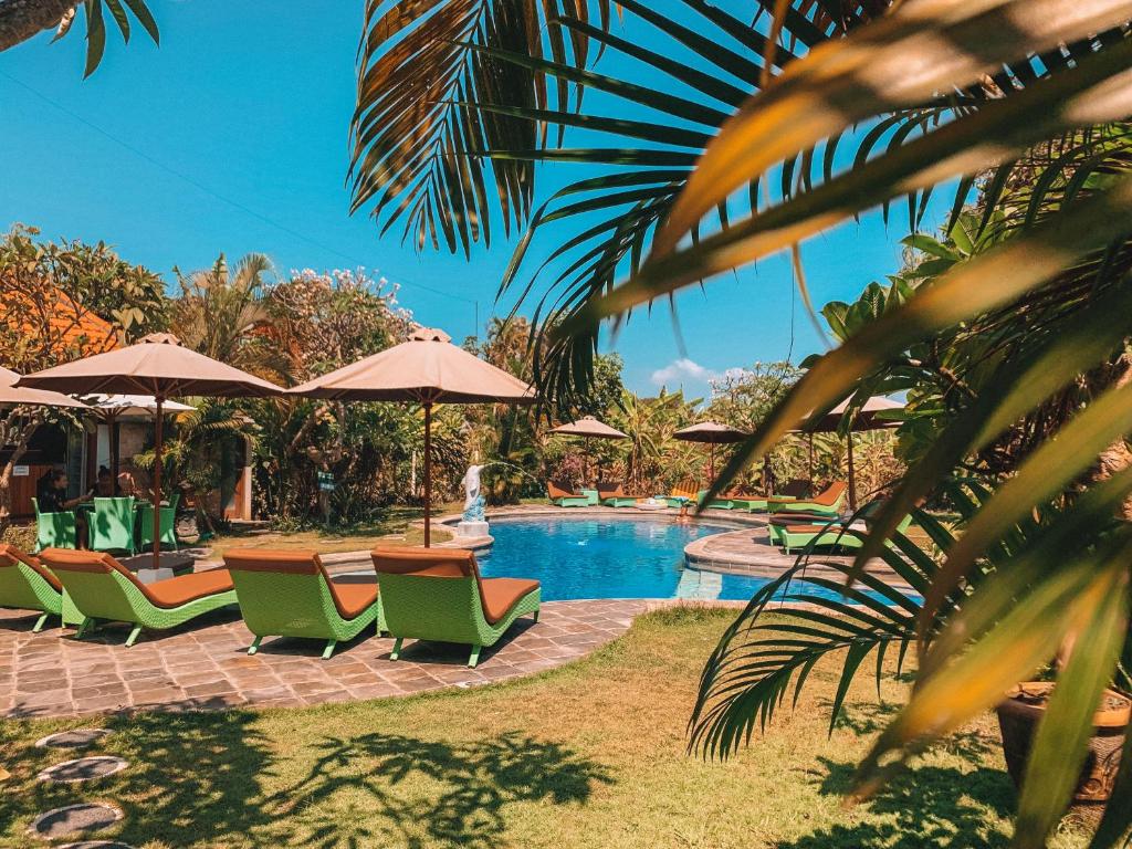 沙努尔巴厘岛维拉萨纳酒店的一个带绿色椅子和遮阳伞的游泳池