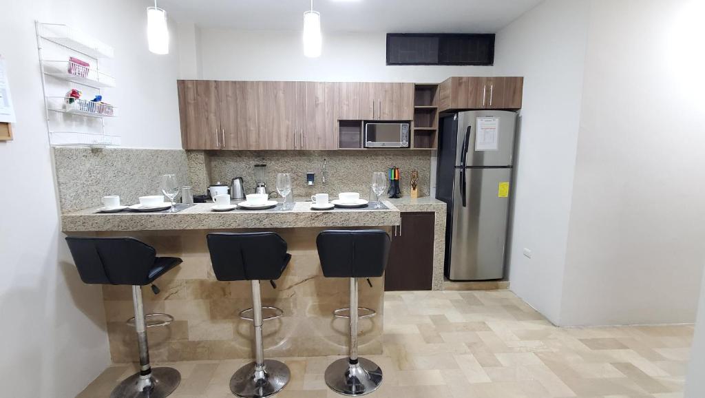 瓜亚基尔NCG SUITE SAMANES的厨房配有带凳子的柜台和冰箱。