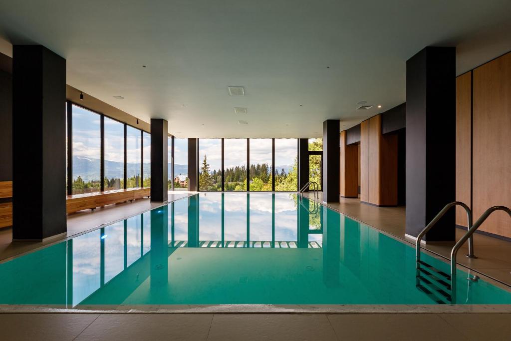 布克维ШПИЦІ Hotel & SPA的一座大型游泳池,设有玻璃窗户,位于大楼内